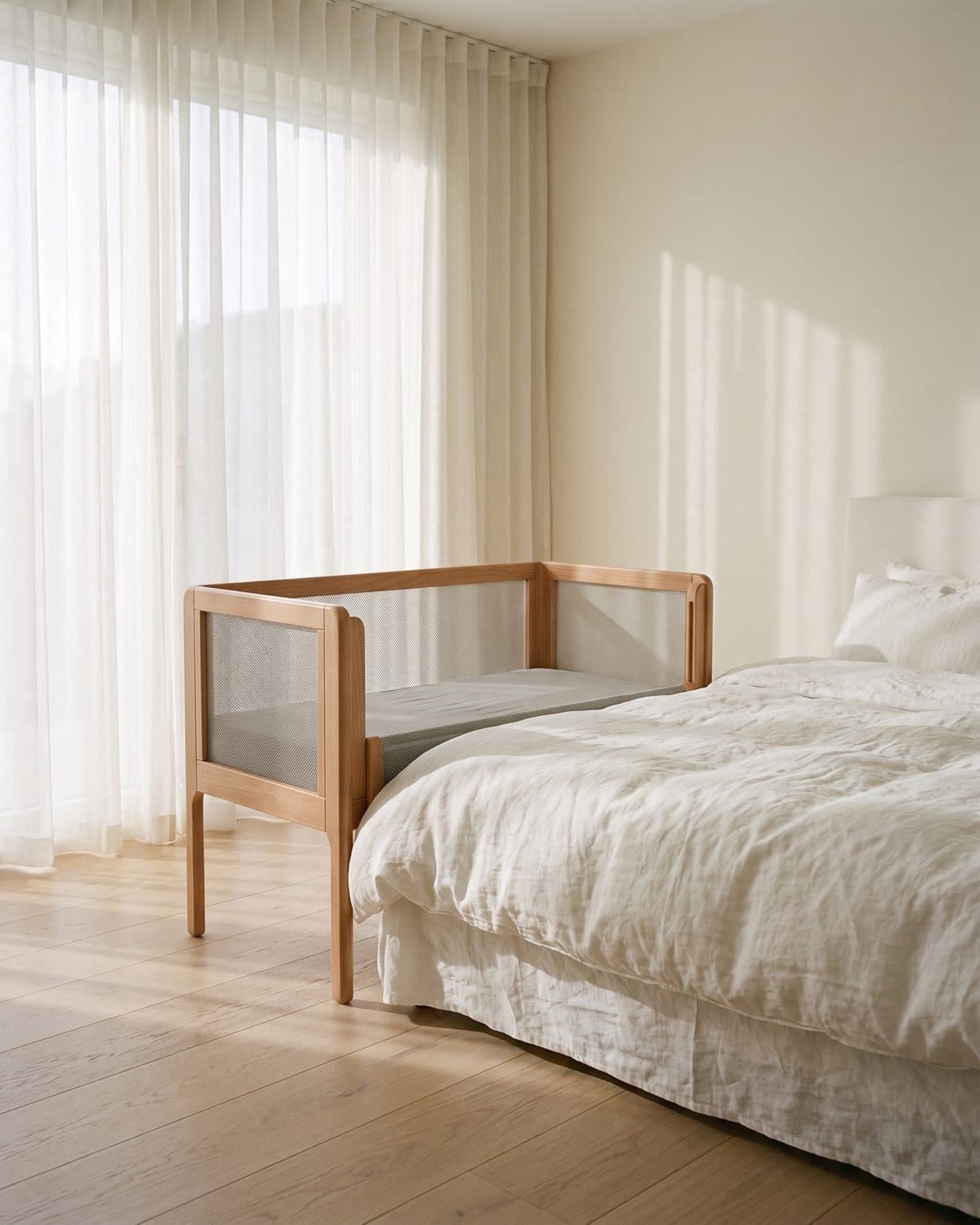 Le cododo Lune accolé à un lit parental aux draps de lin blanc, dans une chambre lumineuse